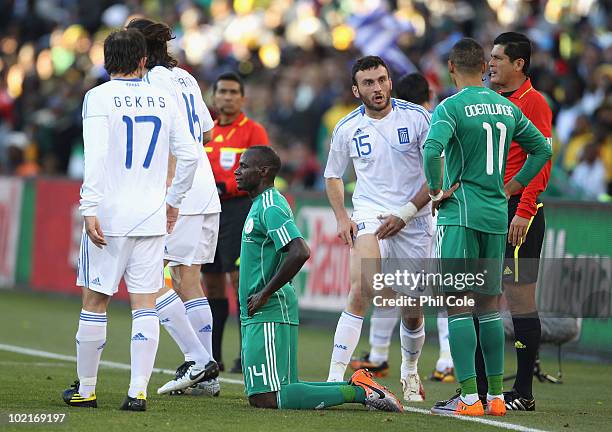 Vassilis Torosidis of Greece shows Peter Odemwingie the marks on his leg after a tackle by Sani Kaita of Nigeria, who kneels on the ground after...