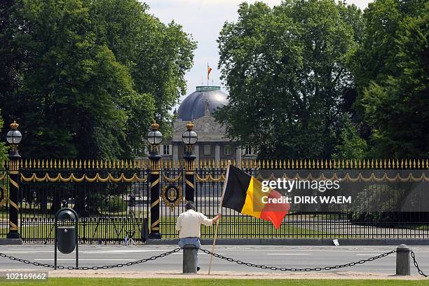 Man sits with a Belgian flag in front of Laeken/Laken royal castle, on June 17, 2010 in Brussels, on the fourth day after the federal elections....