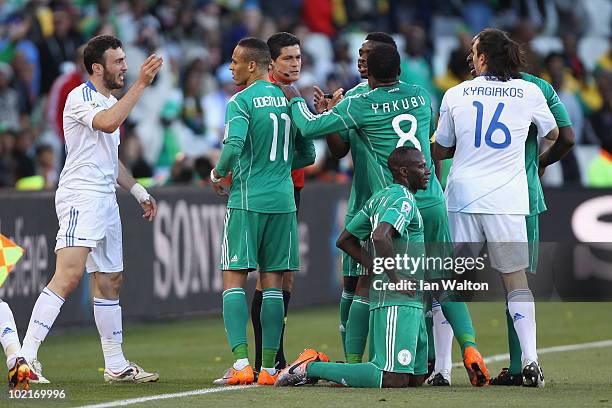 Players argue with referee Oscar Ruiz as Sani Kaita of Nigeria kneels on the ground after being shown a red card during the 2010 FIFA World Cup South...