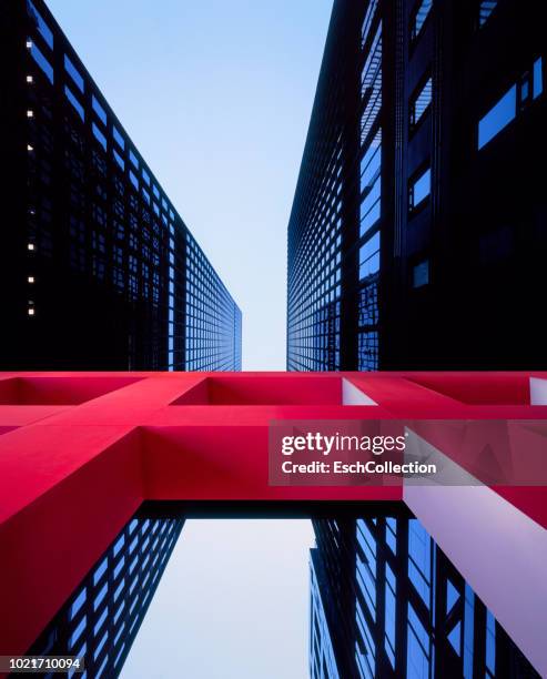 red architectural sculpture in front of modern office buildings - modern sculpture stock pictures, royalty-free photos & images