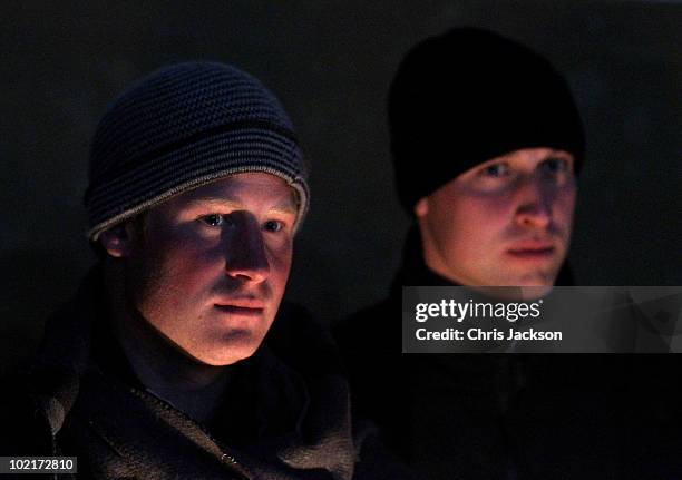 Prince Harry and Prince William look on in the faint candlelight as they visit Semonkong Herd Boy School on June 16, 2010 in Semonkong, Lesotho. The...