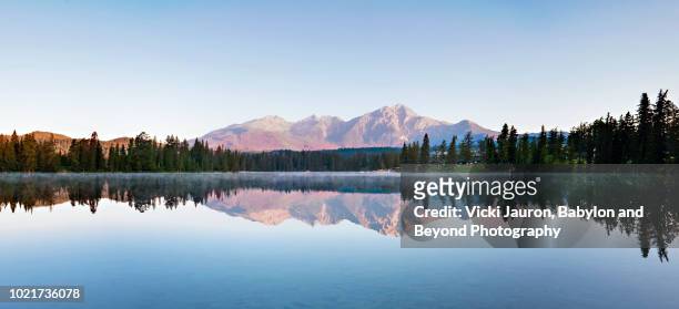 wide panoramic of trees, lake and mountain at lake beauvert, jasper, canada - montañas rocosas canadienses fotografías e imágenes de stock