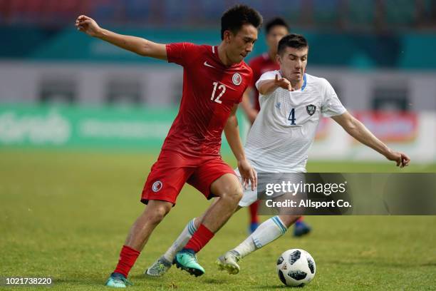 Akramjon Komilov of Uzbekistan holds off Wu Chun Ming of Hong Kong China during the Men's football competition of the last 16 elimination match...