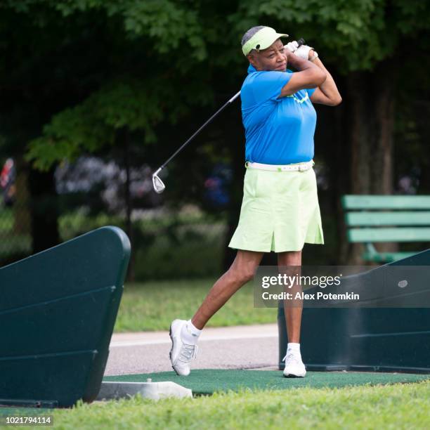 the active, optimistic 77-years-old senior black woman playing golf - senior golf swing stock pictures, royalty-free photos & images