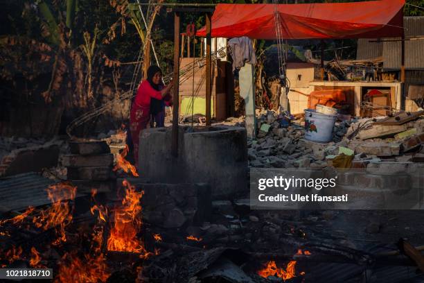 Woman draws water from a well as they clean the ruins of their damaged houses in Pemenang on August 23, 2018 in Lombok island, Indonesia. Thousands...