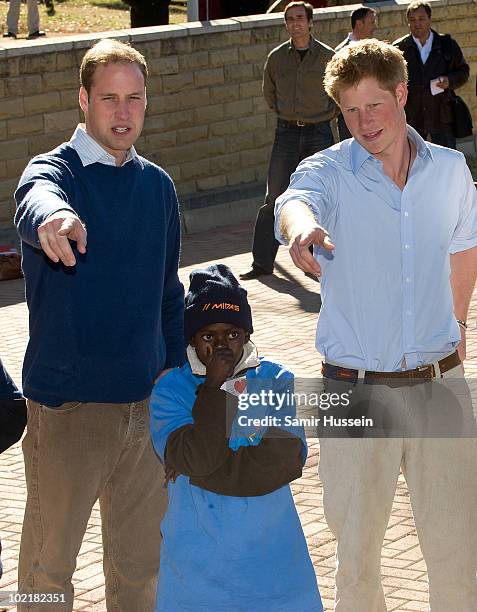 Prince William and Prince Harry meet a child at the Mamohato Network Club for children affected by HIV at King Letsie's Palace on June 17, 2010 in...