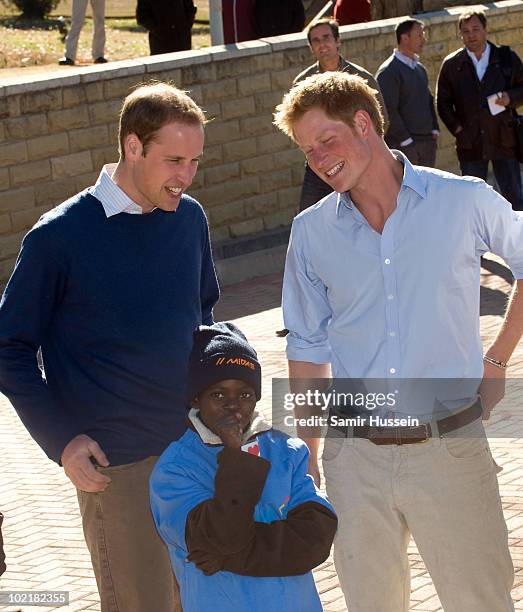 Prince William and Prince Harry meet a child at the Mamohato Network Club for children affected by HIV at King Letsie's Palace on June 17, 2010 in...