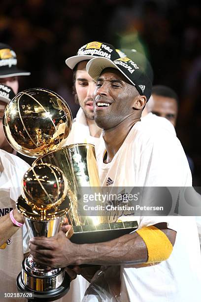 Kobe Bryant of the Los Angeles Lakers struggles to hold both the Larry O'Brien trophy and the MVP trophy after the Lakers defeated the Boston Celtics...
