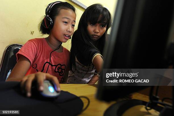 This photograph taken on June 17, 2010 shows two Indonesian 12 year old teenage girls Vinna Erviliana, and Mardiana online on Facebook at an Internet...