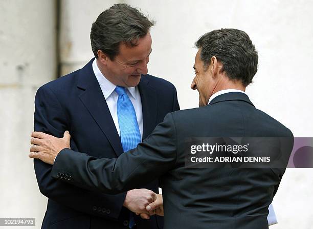 Britain's Prime Minister David Cameron embraces French President Nicolas Sarkozy in between speeches at The Royal Hospital Chelsea in London June 18,...