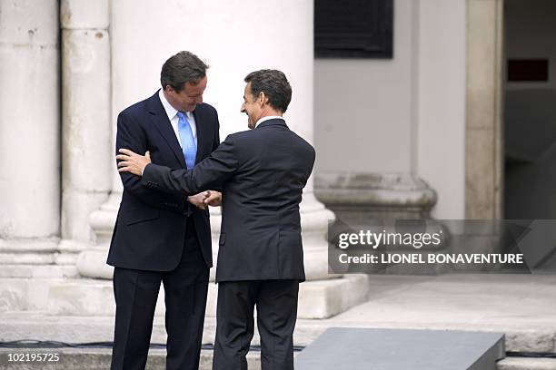 Britain's Prime Minister David Cameron embraces French President Nicolas Sarkozy in between speeches at the royal Chelsea Hospital in London on June...