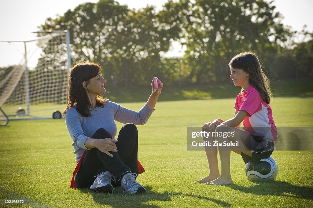 Mom photographing daughter on soccer ball