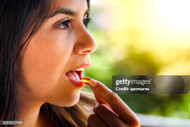 hispanic young woman ready taking a pill with a glass of water in hand - vitamin stock pictures, royalty-free photos & images