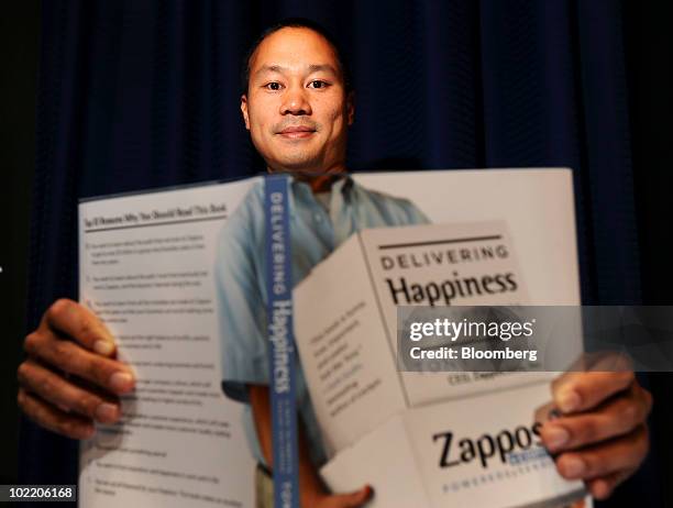 Tony Hsieh, president, founder and chief executive of Zappos.com Inc., poses for a portrait with his autobiography, "Delivering Happiness," in San...