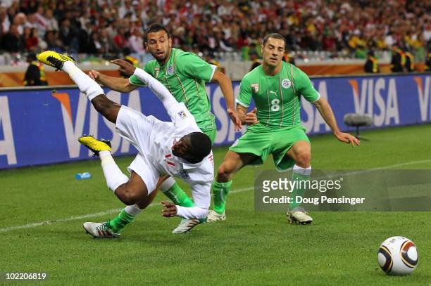 Shaun Wright Phillips of England is tackled by Nadir Belhadj and Medhi Lacen of Algeria during the 2010 FIFA World Cup South Africa Group C match...