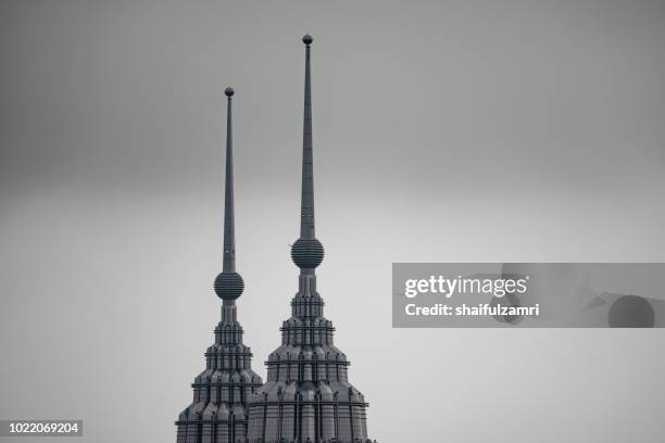 peak of petronas twin towers over cloudy and hazy day in kuala lumpur, malaysia. - petronas towers stock-fotos und bilder