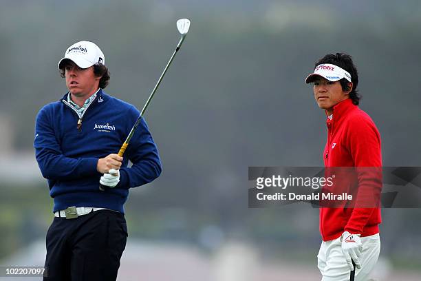 Rory McIlroy of Northern Ireland watches his tee shot on the seventh hole as Ryo Ishikawa of Japan looks on during the second round of the 110th U.S....