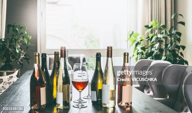 variety of wine bottles and glasses on table in modern living room - empty wine glass stock pictures, royalty-free photos & images