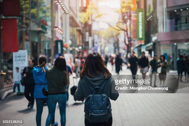 young asian woman traveler traveling and shopping in myeongdong street market at seoul, south korea. myeong dong district is the most popular shopping market at seoul city. - native korean stock-fotos und bilder