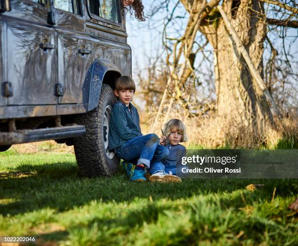 portrait of two boys sitting on a meadow at an off-road vehicle - central europe stock pictures, royalty-free photos & images