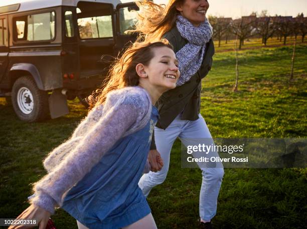 happy mother and daughter running on a meadow at an off-road vehicle - family running stock pictures, royalty-free photos & images