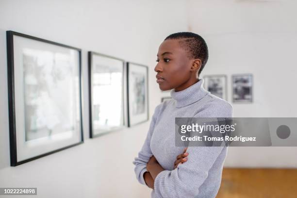 portrait of a young woman in an art gallery looking at pictures - curator fotografías e imágenes de stock
