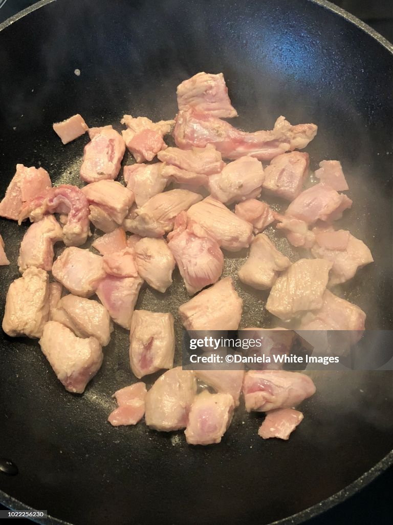 Frying cubed pork meat with bacon