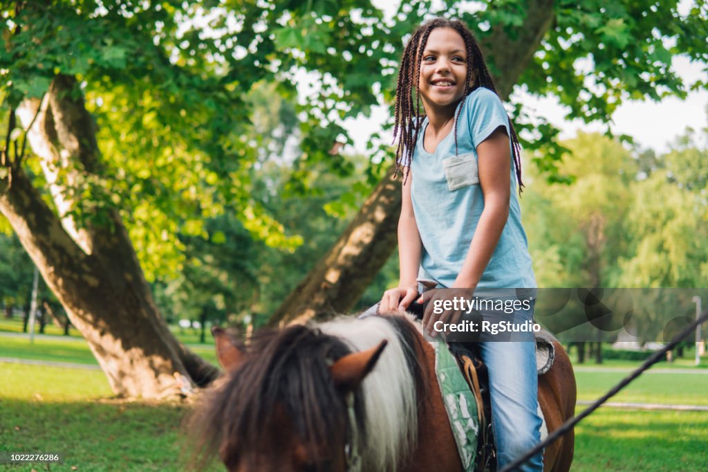 Happy young girl riding a horse
