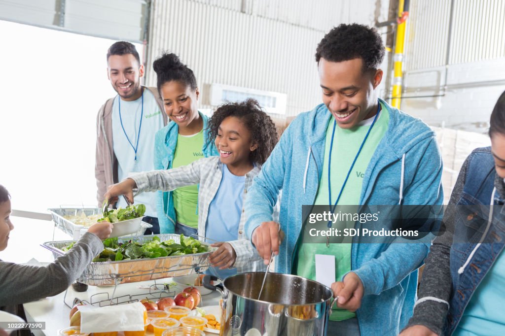 Young man serves soup in soup kitchen