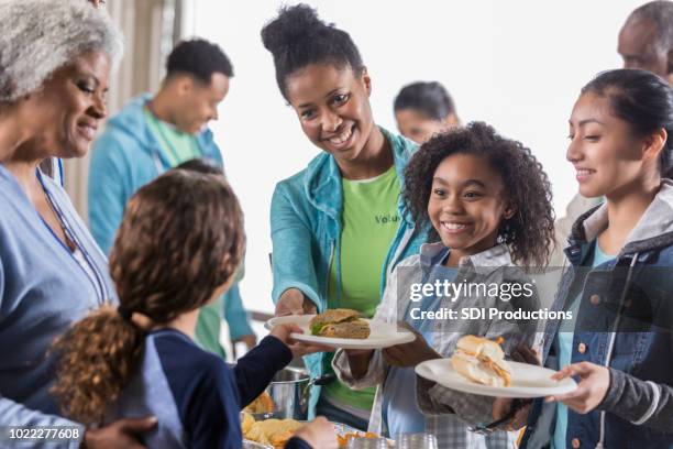 little girl and her mom serve homeless people in soup kitchen - father and children volunteering imagens e fotografias de stock