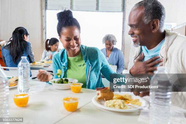 female volunteer has lunch with man in soup kitchen - homeless shelter man stock pictures, royalty-free photos & images
