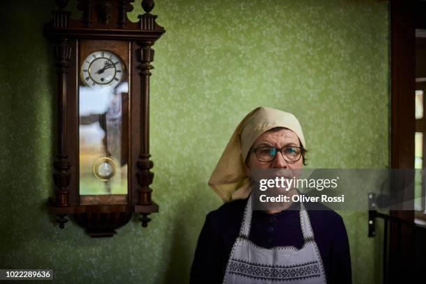 portrait of pensive senior woman at old-fashioned wall clock - reloj de pared fotografías e imágenes de stock