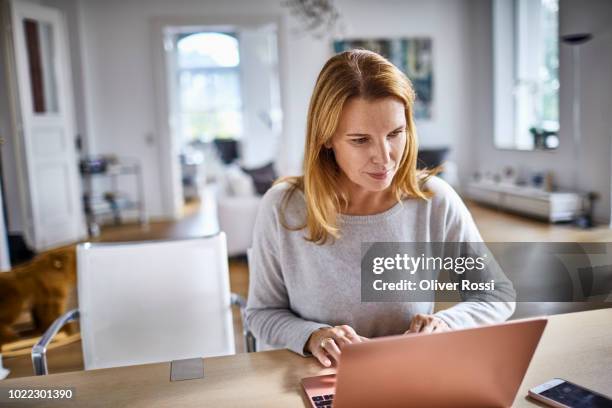 woman using laptop on table at home - homeoffice stock-fotos und bilder