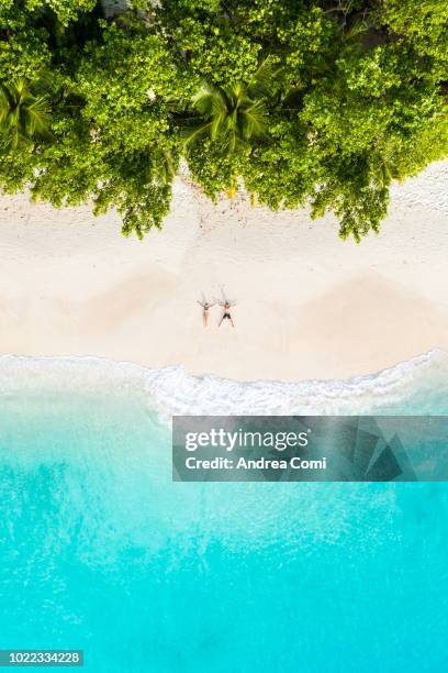 aerial view of a couple lying down on a tropical beach - tropical pattern stock pictures, royalty-free photos & images
