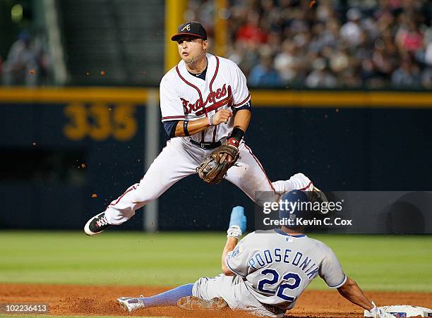 Martin Prado of the Atlanta Braves turns a double play over Scott Podsednik of the Kansas City Royals in the ninth inning at Turner Field on June 19,...