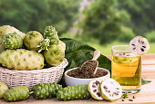Noni fruit juice or Morinda Citrifolia with noni slice and noni powder for health on the wooden background with copy space for text.
