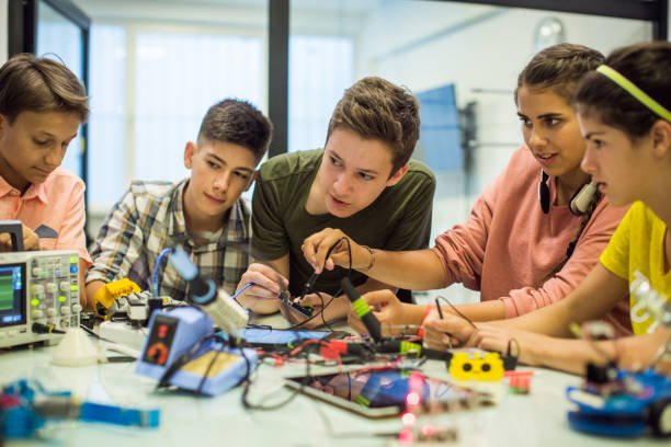 Group of 5 youths working on a electronic project in classroom