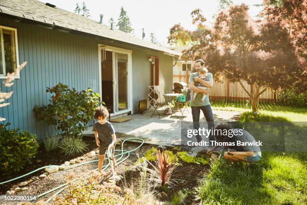 family watering garden in backyard on summer morning - day 5 foto e immagini stock