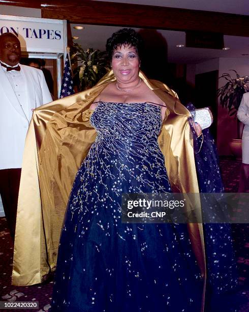 Portrait of American singer Aretha Franklin as she opens her coat to show off her dress for photographers as she attends the 1999 White House...