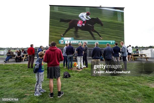 Racegoers in the Clocktower Enclosure watch the replay of the first race at York Racecourse on August 24, 2018 in York, United Kingdom.