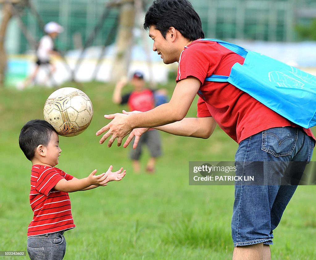 A Taiwanese boy, aided by his father, pr