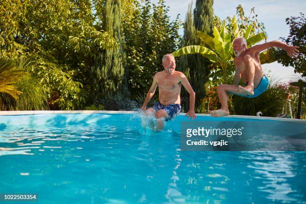 senior friends pool fun - swimming pool jump stock pictures, royalty-free photos & images