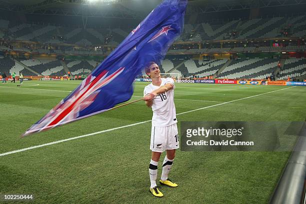 Aaron Clapham of New Zealand waves his country's flag after his team secured a draw in the 2010 FIFA World Cup South Africa Group F match between...