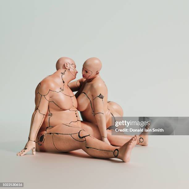 overweight cyborgs: male and female sitting on floor about to kiss - quirky kissing foto e immagini stock