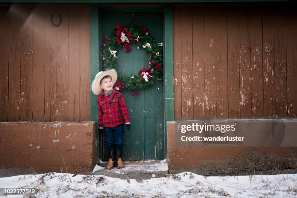 laughing little cowboy and christmas wreath - wreath on barn door stock pictures, royalty-free photos & images