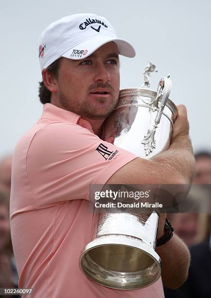 Graeme McDowell of Northern Ireland celebrates with the trophy on the 18th green after winning the 110th U.S. Open at Pebble Beach Golf Links on June...