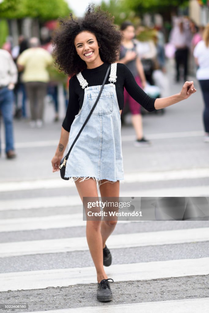 Portrait of happy young woman walking on zebra crossing