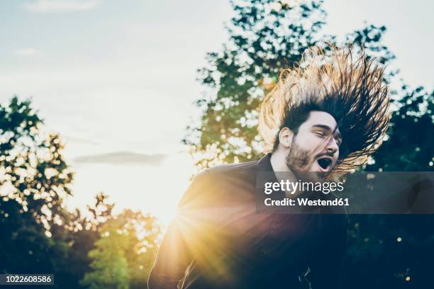 heavy metal fan headbanging in a park - heavy metal stock-fotos und bilder