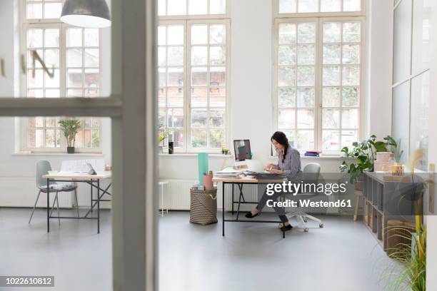 woman working at desk in a loft office - independence imagens e fotografias de stock