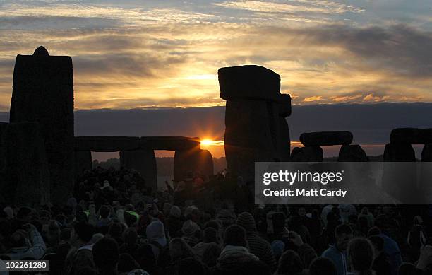 Revellers watch as the midsummer sun rises just after dawn over the megalithic monument of Stonehenge on June 21, 2010 on Salisbury Plain, England....